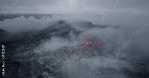Wide pan right aerial, smoke rises from active volcano