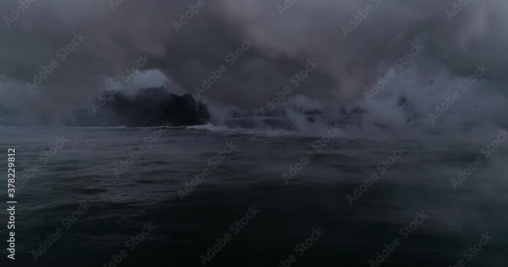 Slow motion aerial, smoke rises from lava meeting ocean Slow motion aerial, smoke rises from lava meeting ocean