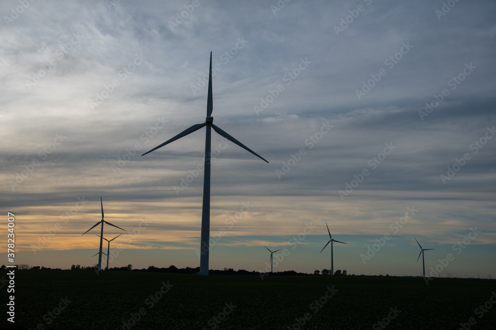 Obraz premium Sunset behind a field of wind turbines
