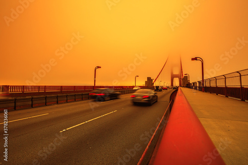Cars crossing Golden Gate Bridge from Presidio to north. Smoky orange sky the bridge of San Francisco city for California fires in in America. Composition about wildfires and climate change concept.