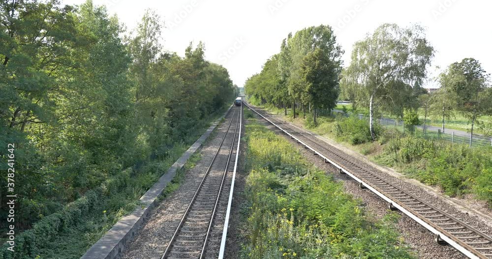 Outdoor aerial top view over railway with moving S-Bahn train on the track on countryside in Berlin, Germany. Outdoor aerial top view over railway with moving S-Bahn train on the track on countryside in Berlin, Germany.