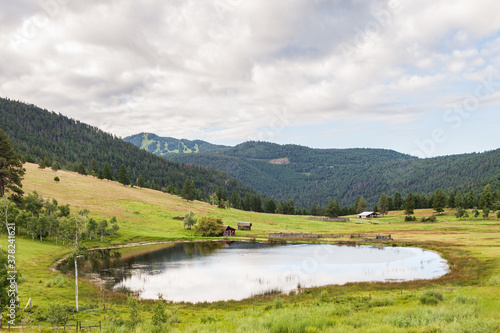 Large pond in swampy meadow among rolling hills country side british columbia Canada
