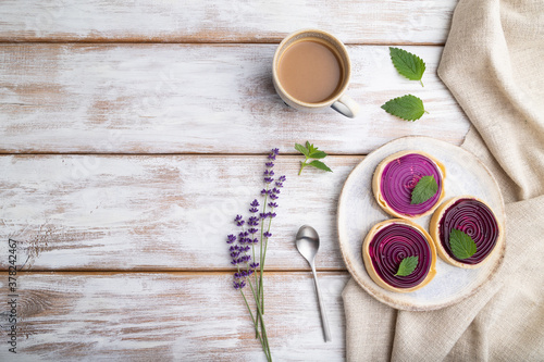 Sweet tartlets with jelly and milk cream with cup of coffee on a white wooden background. top view, copy space.