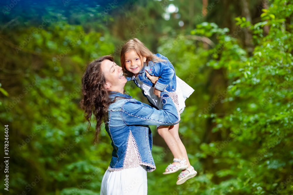 Portrait of Positive Young Caucasian Mother with Her Daughter Playing Together in Green Summer Forest