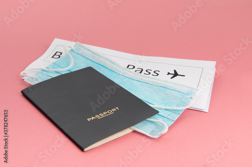a passport, a boarding pass and a surgical mask suggesting the new normal for air travel after covid-19