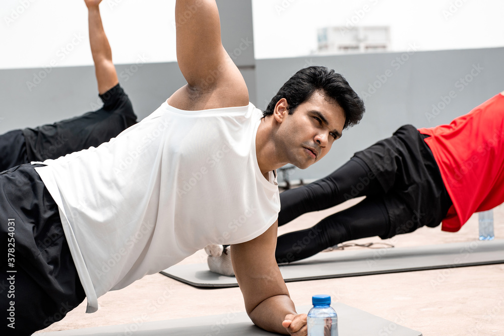 Group of athletic men doing side plank morning workout exercise outdoors on rooftop floor Group of athletic men doing side plank morning workout exercise outdoors on rooftop floor