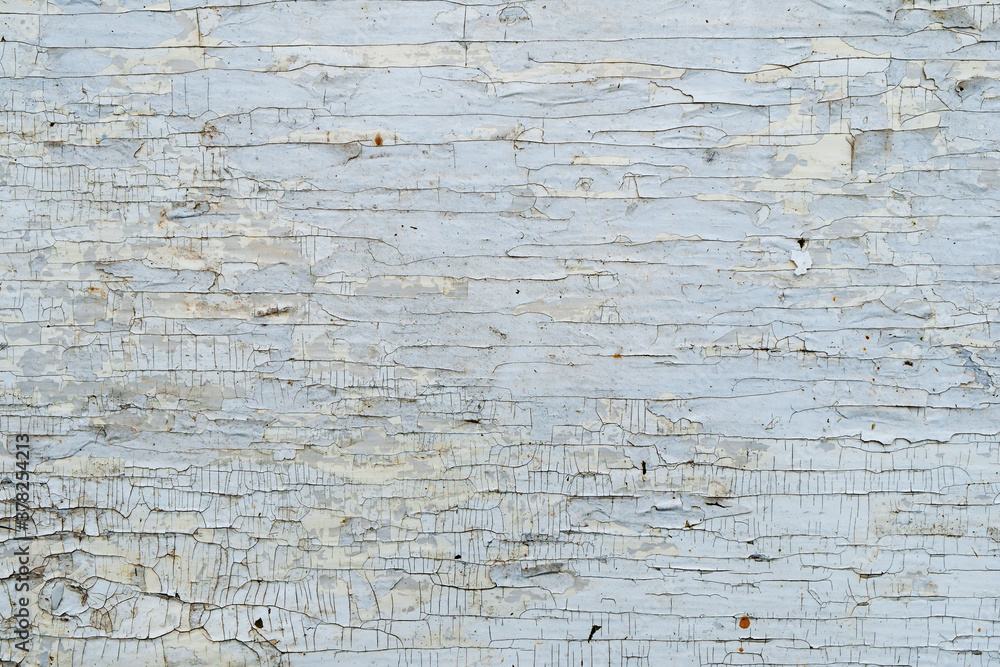 Fototapeta premium The texture of an old surface covered with white paint, cracked and peeling from time.