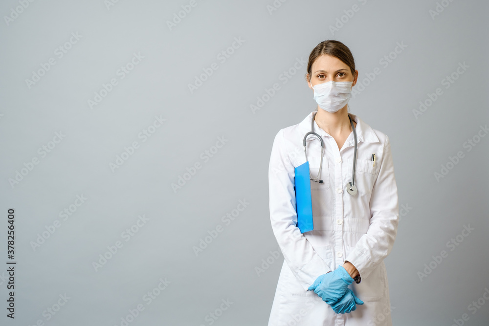 Happy doctor wearing surgical mask isolated on gray