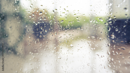 blurry garden view through window with rain drops in warm theme
