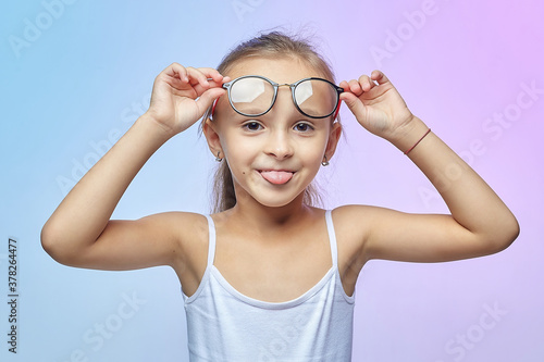 attractive little girl with glasses shows her tongue