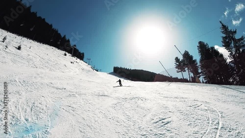 Young athlete skiing in Bansko Pirin mountains on sunny day - Skier riding down the black ski piste, slow motion photo