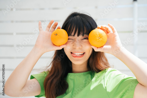Young asian woman traveler wearing green shirt holding two oranges.