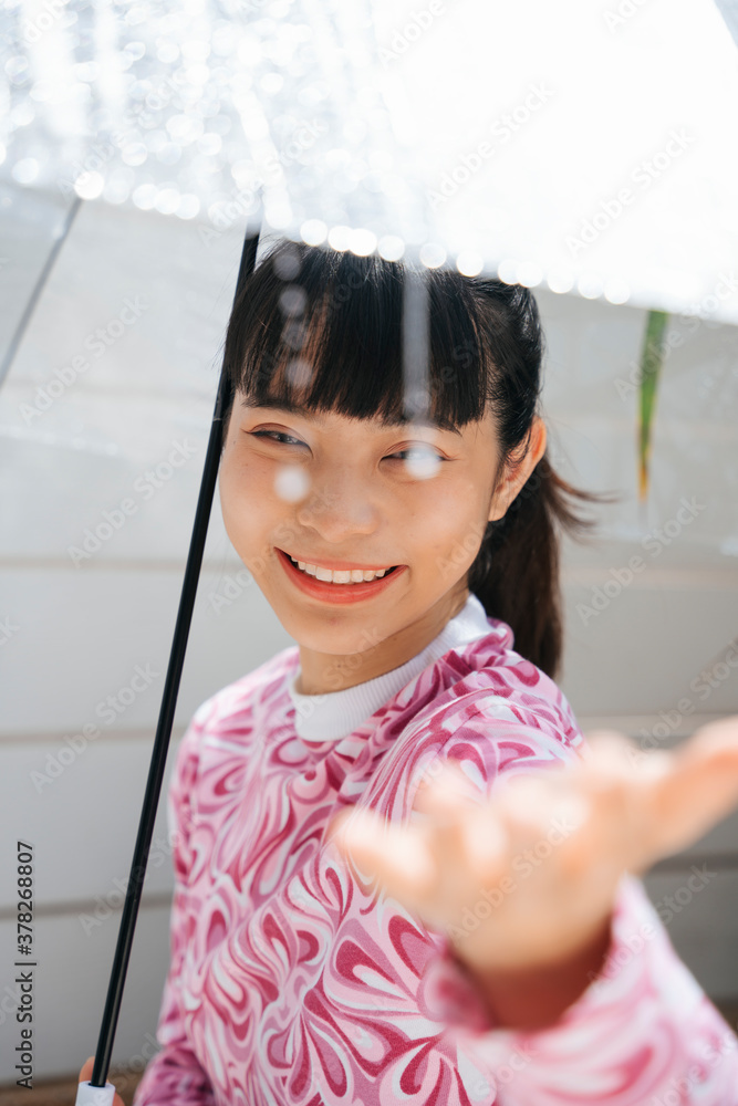 Asian woman in pink shirt holding transparent umbrella touching raindrop in sunny day. Asian woman in pink shirt holding transparent umbrella touching raindrop in sunny day.