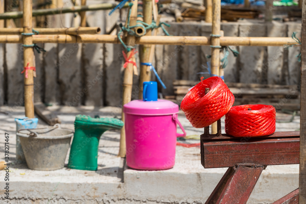 Red plastic rope roll on steel bar over blurred construction site, outdoor day light Red plastic rope roll on steel bar over blurred construction site, outdoor day light