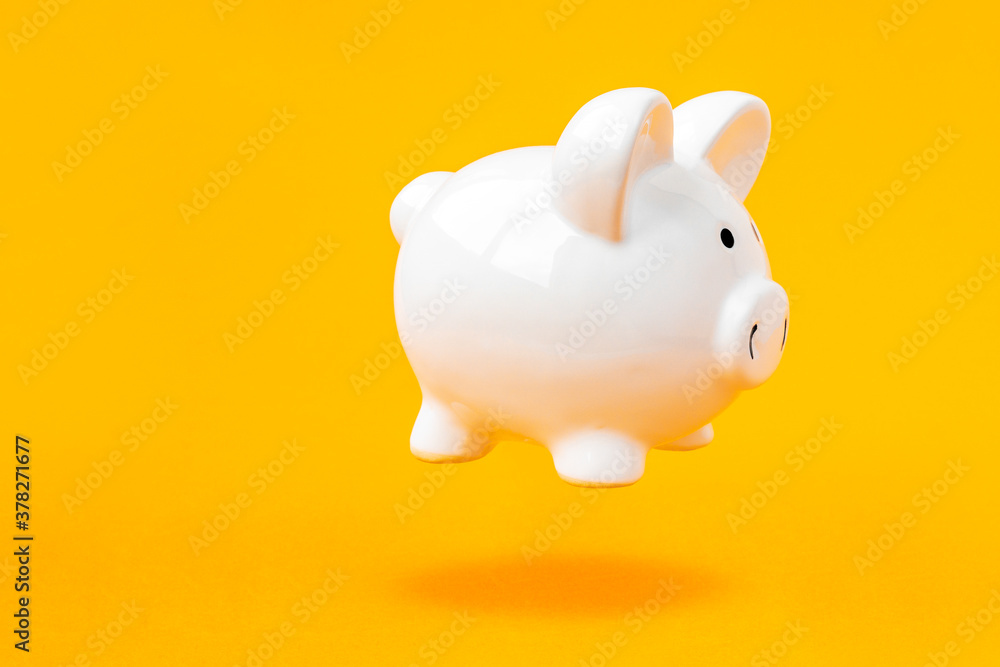 Piggy bank levitating over a yellow background Piggy bank levitating over a yellow background