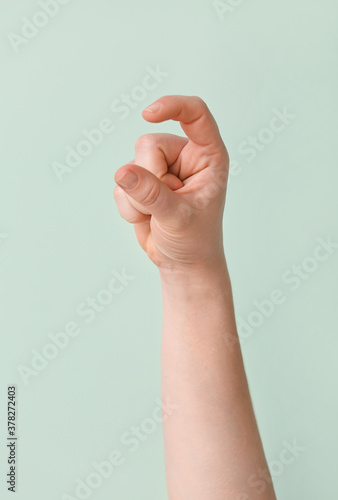 Hand showing letter X on color background. Sign language alphabet