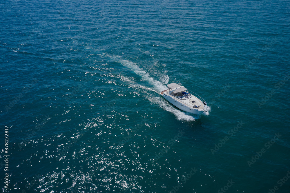 White high-speed yacht in motion top view, high speed, water splashes. Aerial view luxury motor boat White high-speed yacht in motion top view, high speed, water splashes. Aerial view luxury motor boat