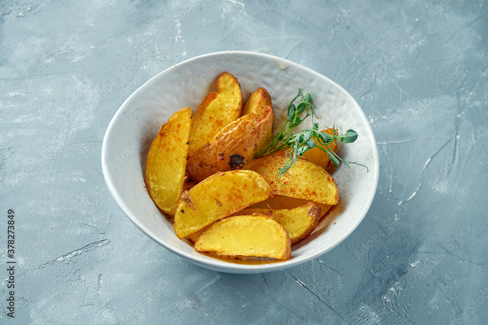 Selyansky baked potatoes in spices in a white bowl on a gray background. Baked potato wedges Selyansky baked potatoes in spices in a white bowl on a gray background. Baked potato wedges