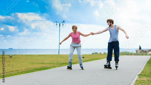 Young couple holding hands while rollerblading