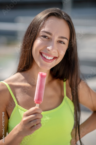 Girl in yellow top smiling and holding ice-cream