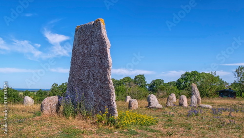 Viking stone ship burial and old windmill in Oland island by beautiful day, Gettlinge, Sweden photo