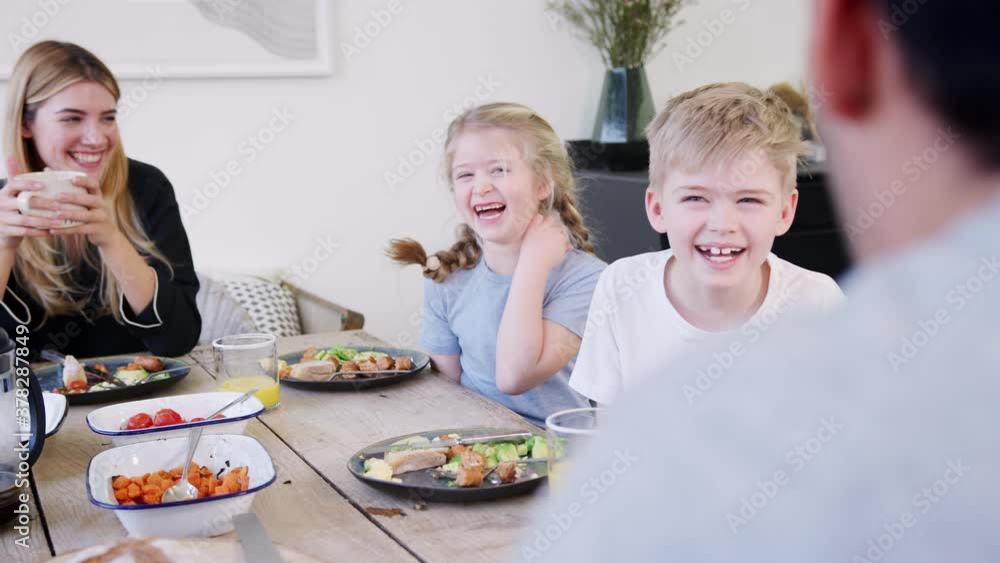 Family sitting around table at home in pyjamas enjoying brunch together - shot in slow motion Family sitting around table at home in pyjamas enjoying brunch together - shot in slow motion