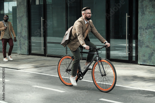 Photos Mature businessman riding to his work by bike along the streets in the city