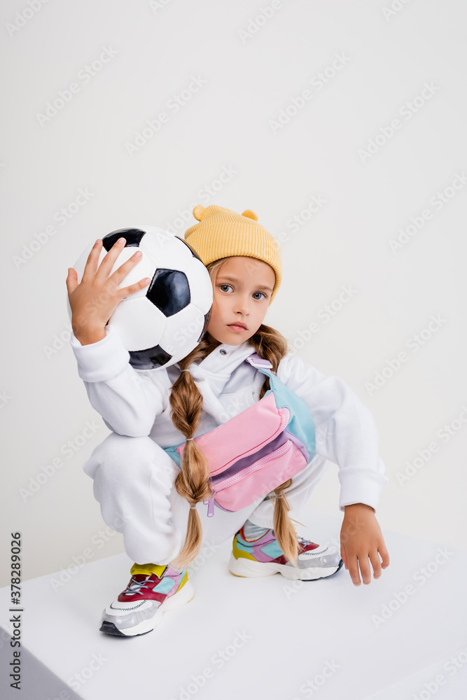 blonde girl in sportswear posing with soccer ball on cube isolated on white  Stock Photo | Adobe Stock