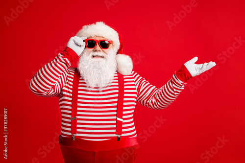 Portrait of his he nice attractive handsome cheerful cheery Santa demonstrating copy space gift present surprise bargain offer isolated on bright vivid shine vibrant red color background © deagreez