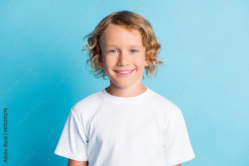 Portrait of pretty boy look in camera beaming smiling wear white t-shirt isolated over blue color background Portrait of pretty boy look in camera beaming smiling wear white t-shirt isolated over blue color background