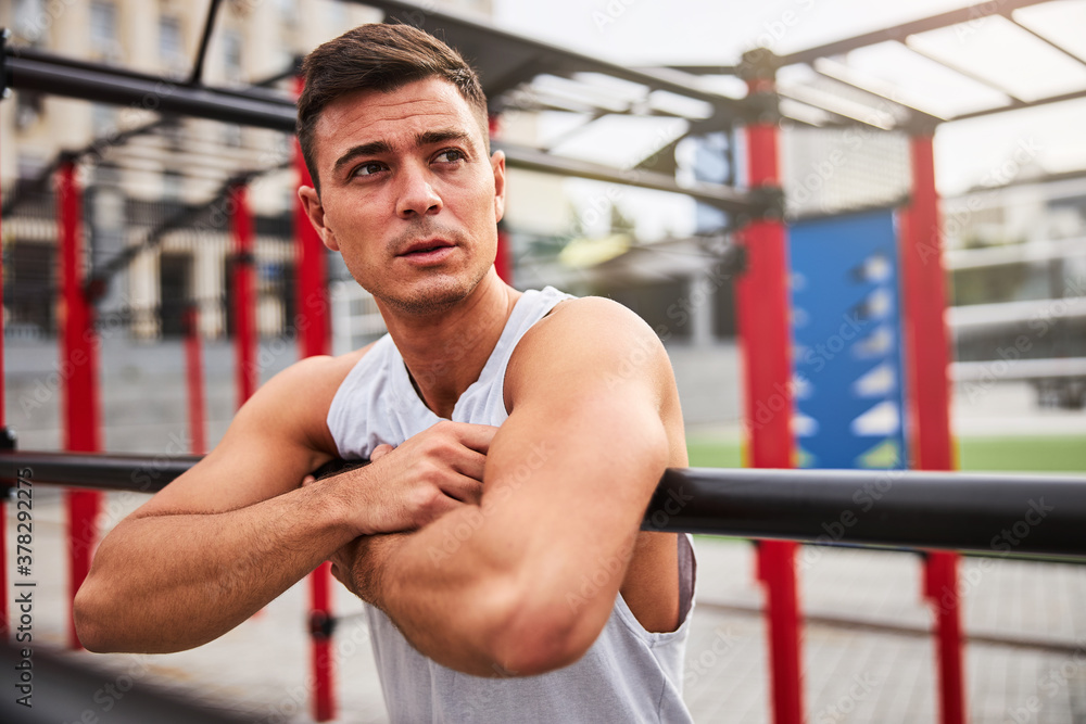 Strong handsome guy training alone on sports ground Strong handsome guy training alone on sports ground