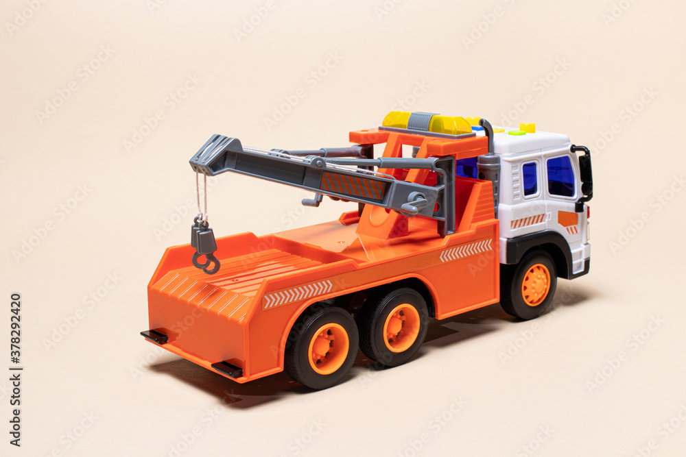Toy orange tow truck on beige background. Children's car for loading and transporting cars.