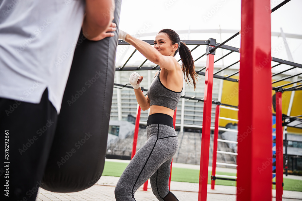 Obraz premium Jolly young woman during boxing workout outdoors