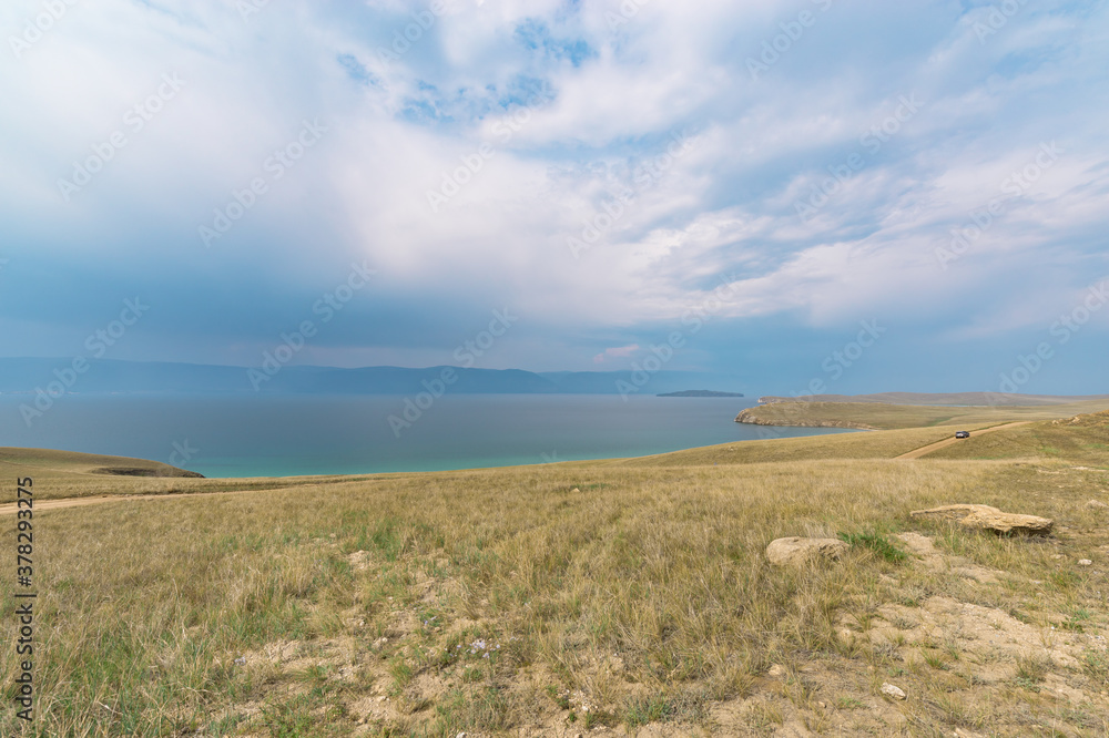 Picturesque sky over the Maloye More Strait. Federal highway on the steppe coast of Olkhon Island.