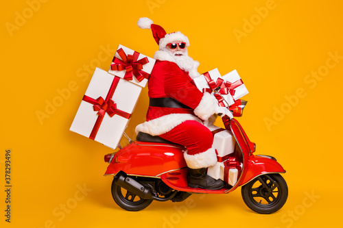 Full size profile side photo of white grey hair bearded santa claus ride motorbike deliver x-mas christmas gifts on noel night wear headwear isolated bright shine color background