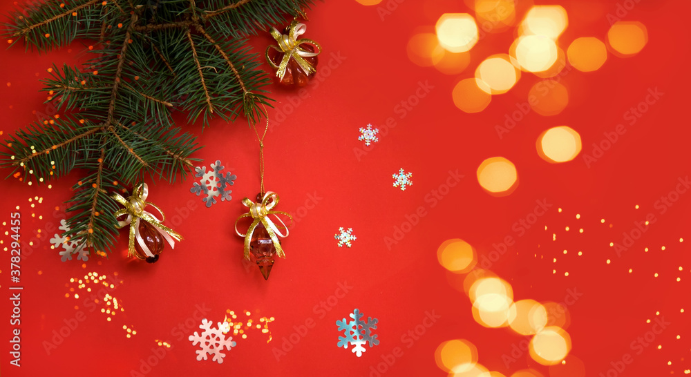 Spruce branch decorated with Christmas decorations on a red background with snowflakes and bokeh. christmas banner Spruce branch decorated with Christmas decorations on a red background with snowflakes and bokeh. christmas banner