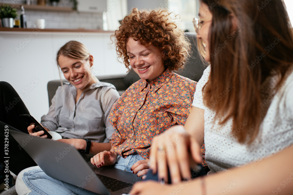 © JustLife - Girlfriends talking and laughing in office. Beautiful women drinking coffee in the office...