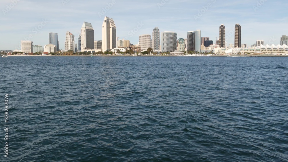 Fototapeta premium Metropolis urban skyline, highrise skyscrapers of city downtown, San Diego Bay, California USA. Waterfront buildings near pacific ocean harbour. View from boat, nautical public transport to Coronado