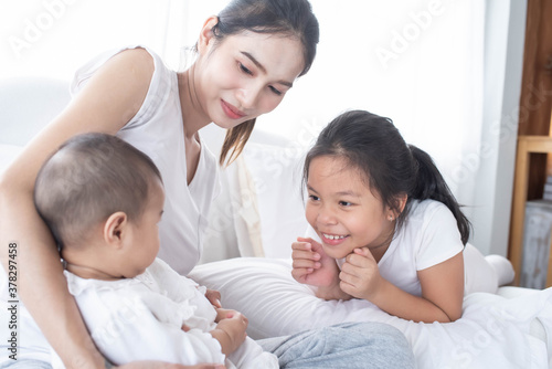 happy loving family. Love, trust and tenderness concept. Mother and child on a white bed. Parent and little kid relaxing at home. Mother and her daughters children girls playing and hugging.