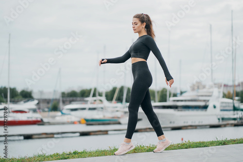 slender woman walking doing exercises on the background of yachts, positive mood and thoughts about the right healthy lifestyle health