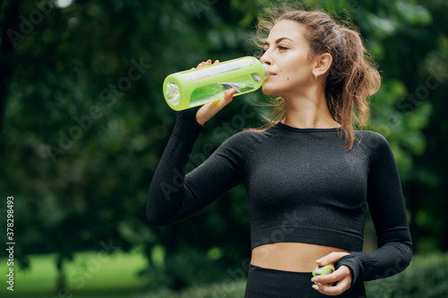 the woman looks great, athletic body, drinking water after a workout, the feeling of thirst. Portrait of a Caucasian woman, sweet, strong, confident photo