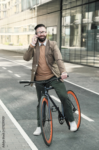 Successful businessman talking on mobile phone during his ride on a bike in the city