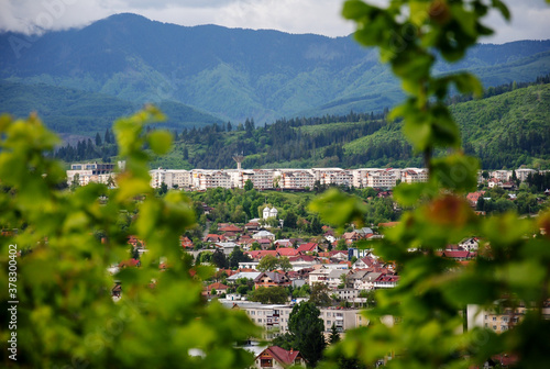 Large working glass residential area in Campulung Muscel, a town in Arges County, Romania - framed by tree branches