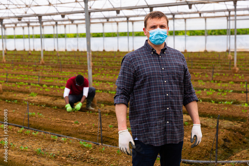 Portrait of confident owner of greenhouse wearing medical face mask. New reality during coronavirus pandemic