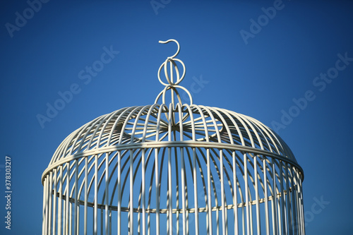 Top part of a retro white metal cage against blue sky