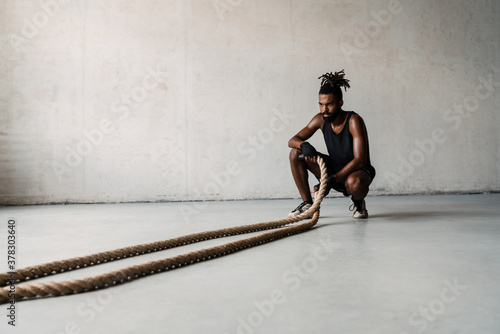 Quadro em tela Image of african american sportsman working out with battle ropes