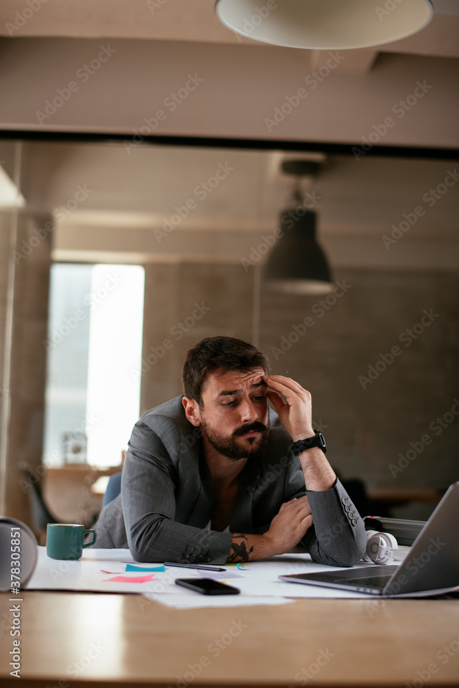 Young businessman working on projects. Tired businessman in suit working in the office. Young businessman working on projects. Tired businessman in suit working in the office.