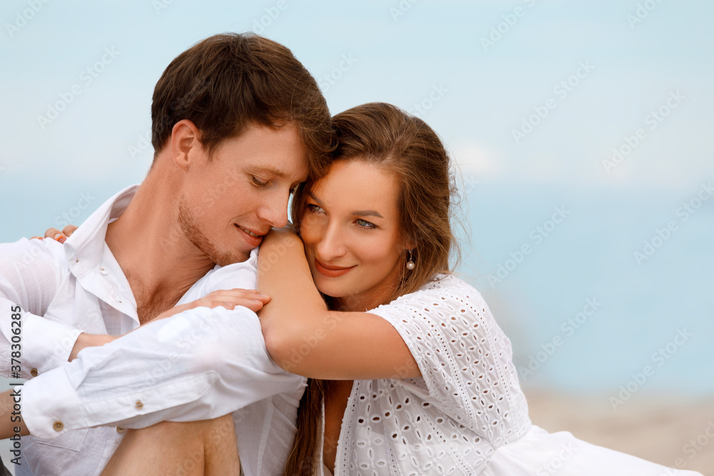 Portrait of a sweet couple of young lovers resting on the beach