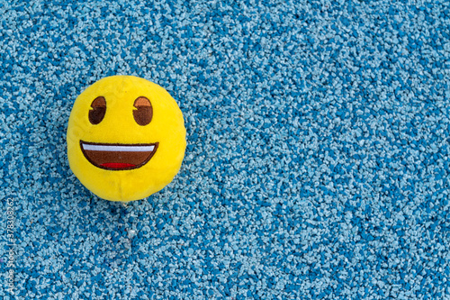 Toy textile yellow ball with smile on green background