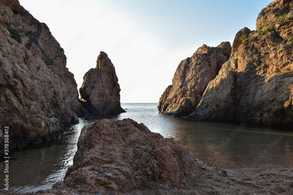 Rocks in the water at Tossa de Mar beach photographed at sunrise.